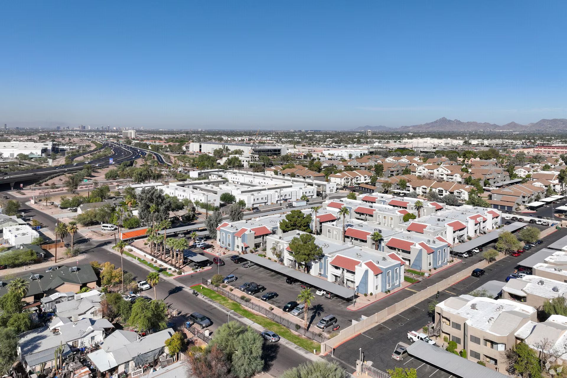 Aerial view of a colorful low-rise apartment complex in a suburban neighborhood with roads and homes nearby