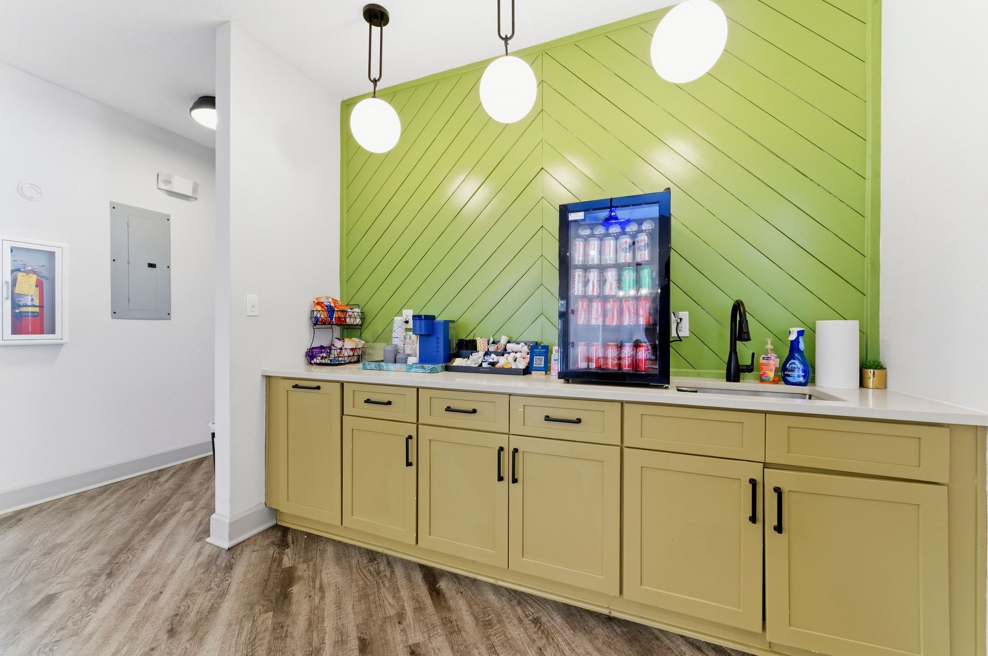 Office break room with green accent wall, countertop, and refrigerated beverage cooler