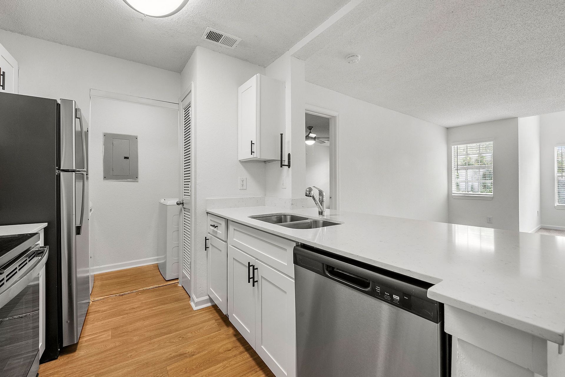 Modern white kitchen with stainless appliances, white cabinets, and wood floors