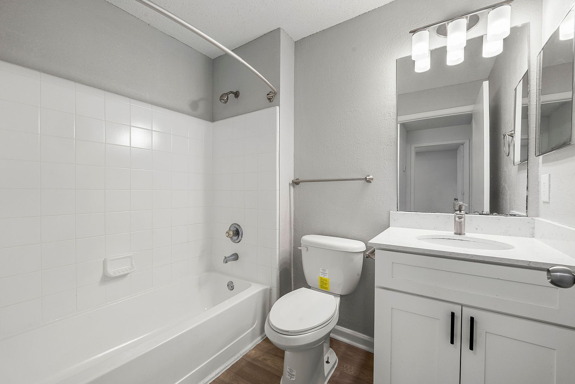 Bright white bathroom with bathtub, toilet, vanity sink, and large mirror