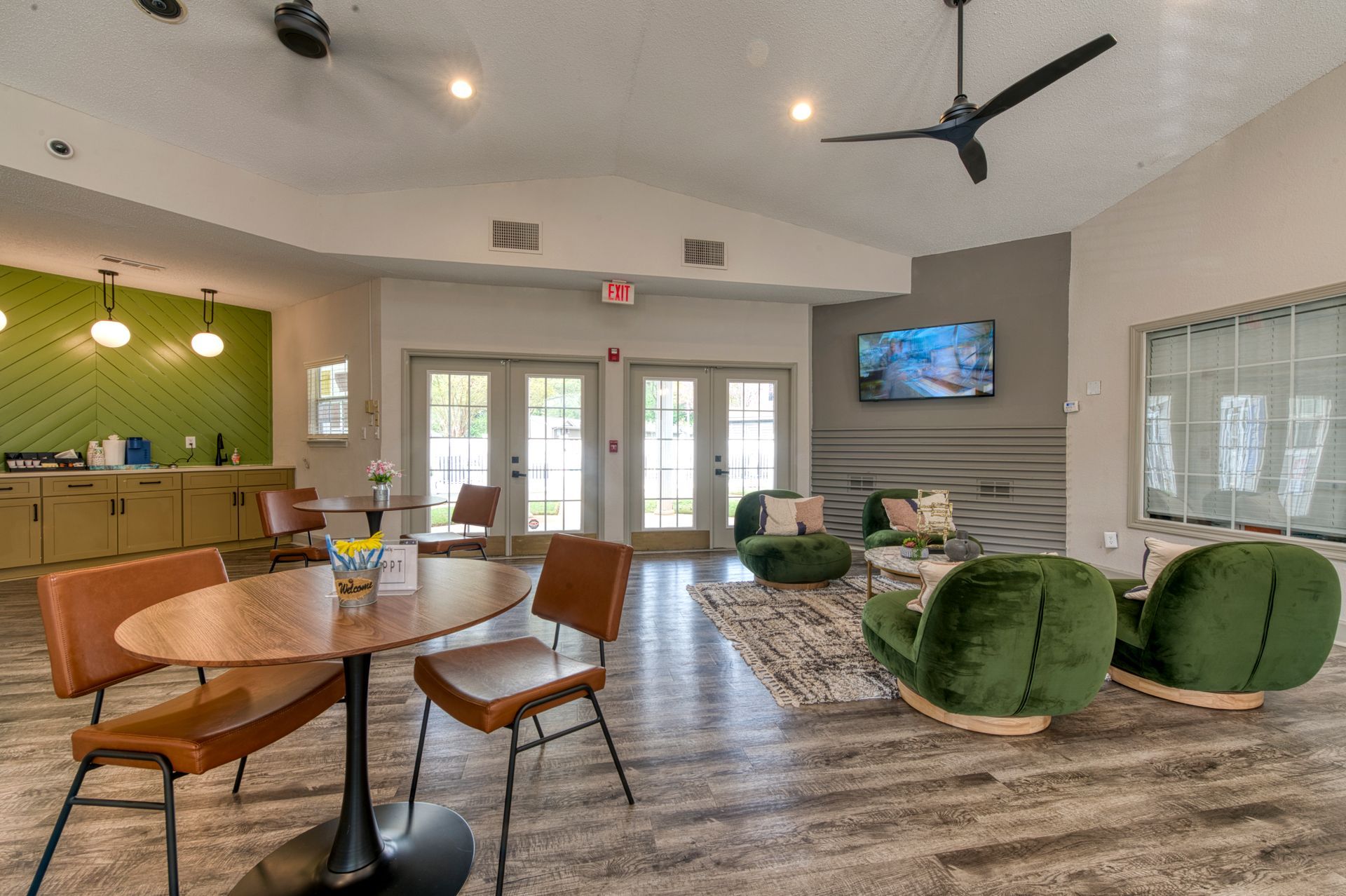 Modern lobby lounge with round tables, green chairs, sofa, TV, fireplace, and large windows