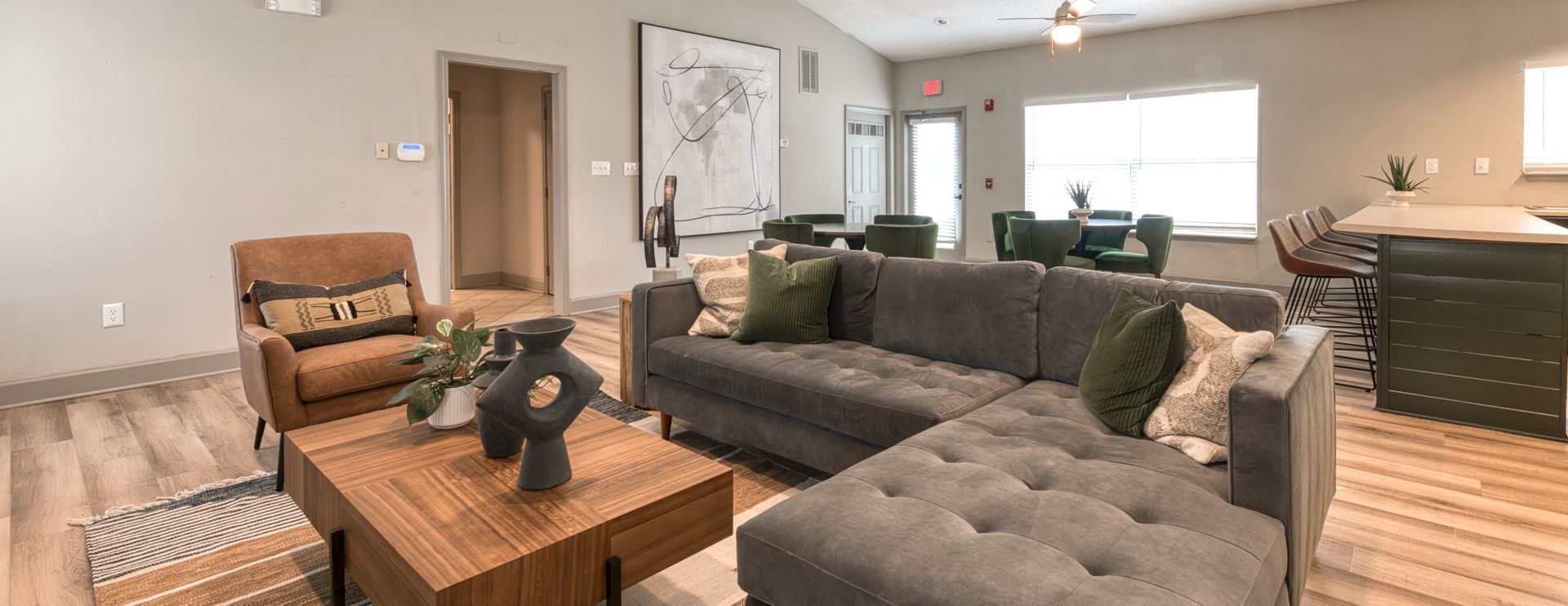 Modern living room with gray sectional sofas, wooden coffee table, armchair, and large window.