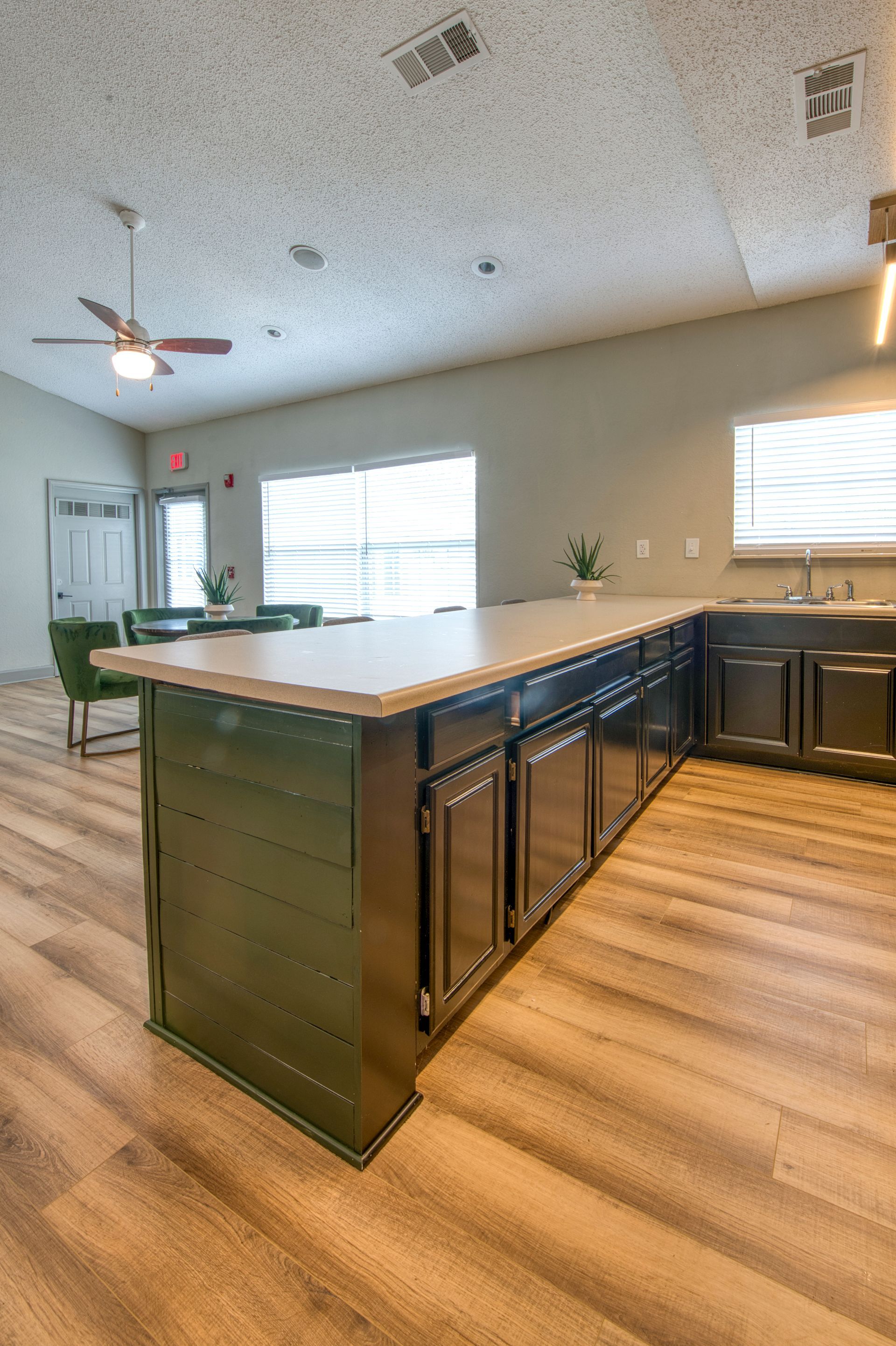 Modern kitchen with a large island, dark cabinets, wood floors, and bright windows