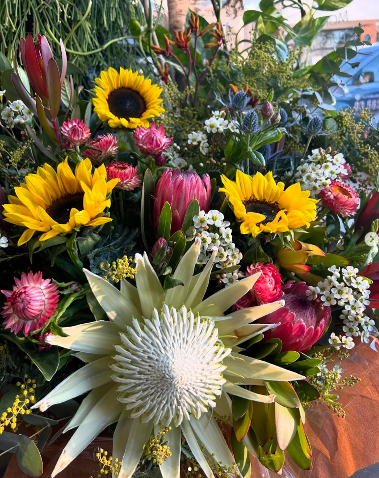 A vase of flowers is sitting on a counter in front of a wakefield vogrig & boote sign.