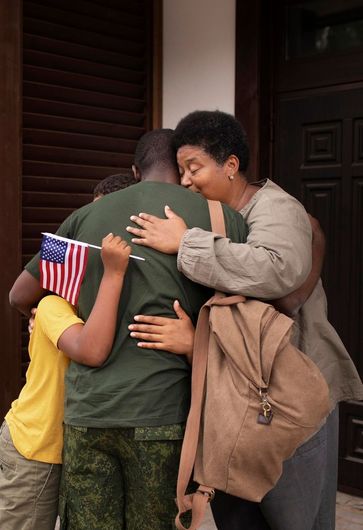 A woman is hugging a soldier who is holding an american flag