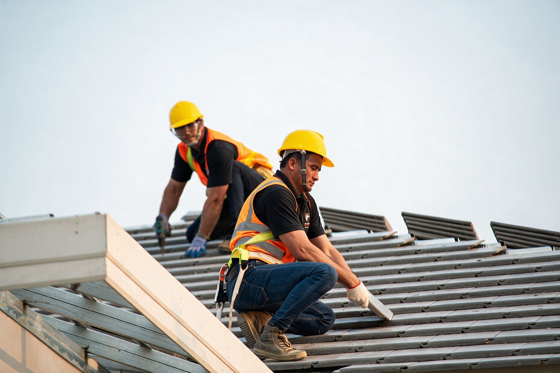 Worker in a yellow hard hat installing a metal roof panel outdoors