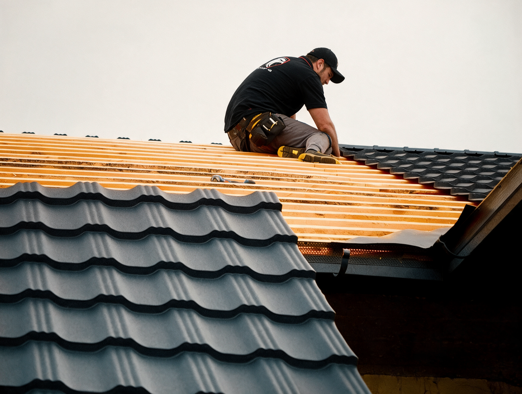 Worker installing roofing panels on a house roof
