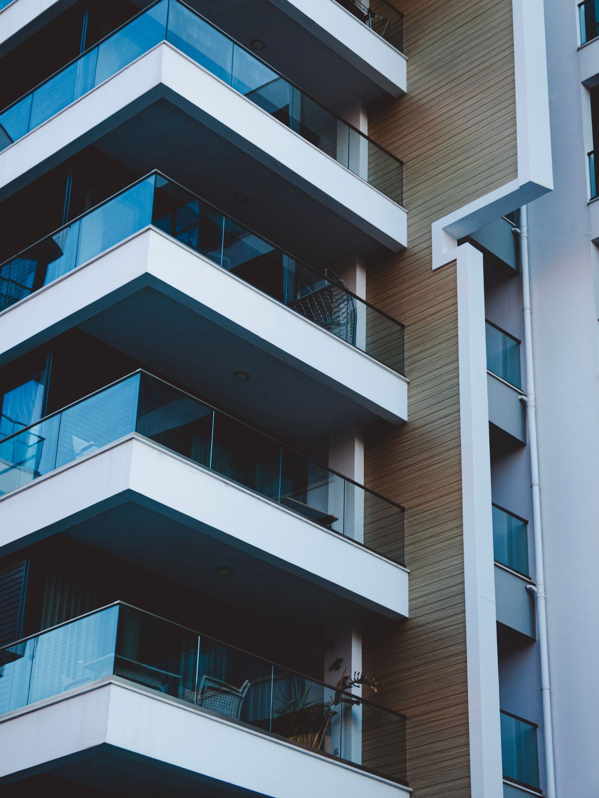 Modern apartment balconies with blue glass railings on a brick building facade