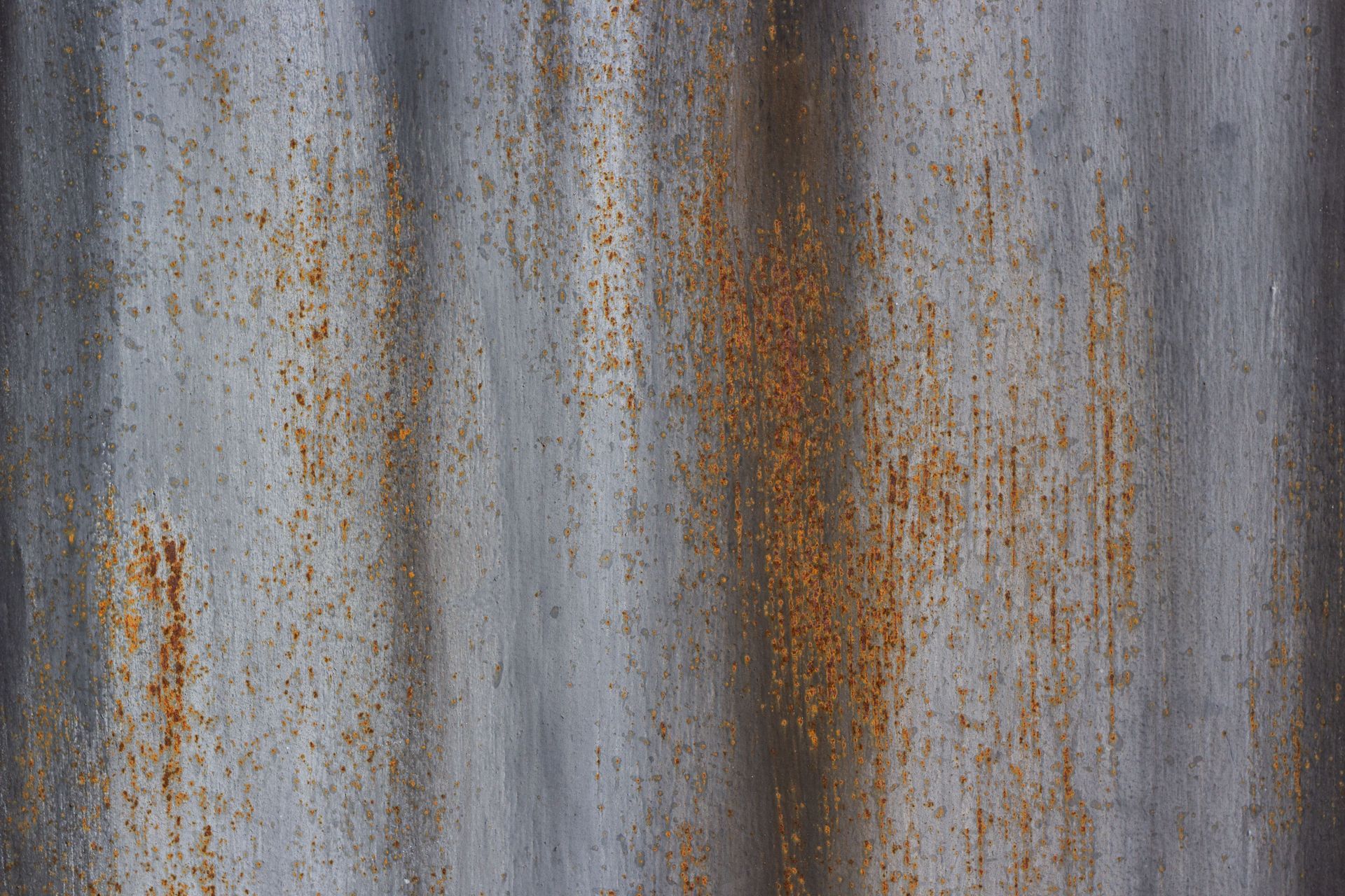 Weathered corrugated metal with gray and rust-streaked vertical stains