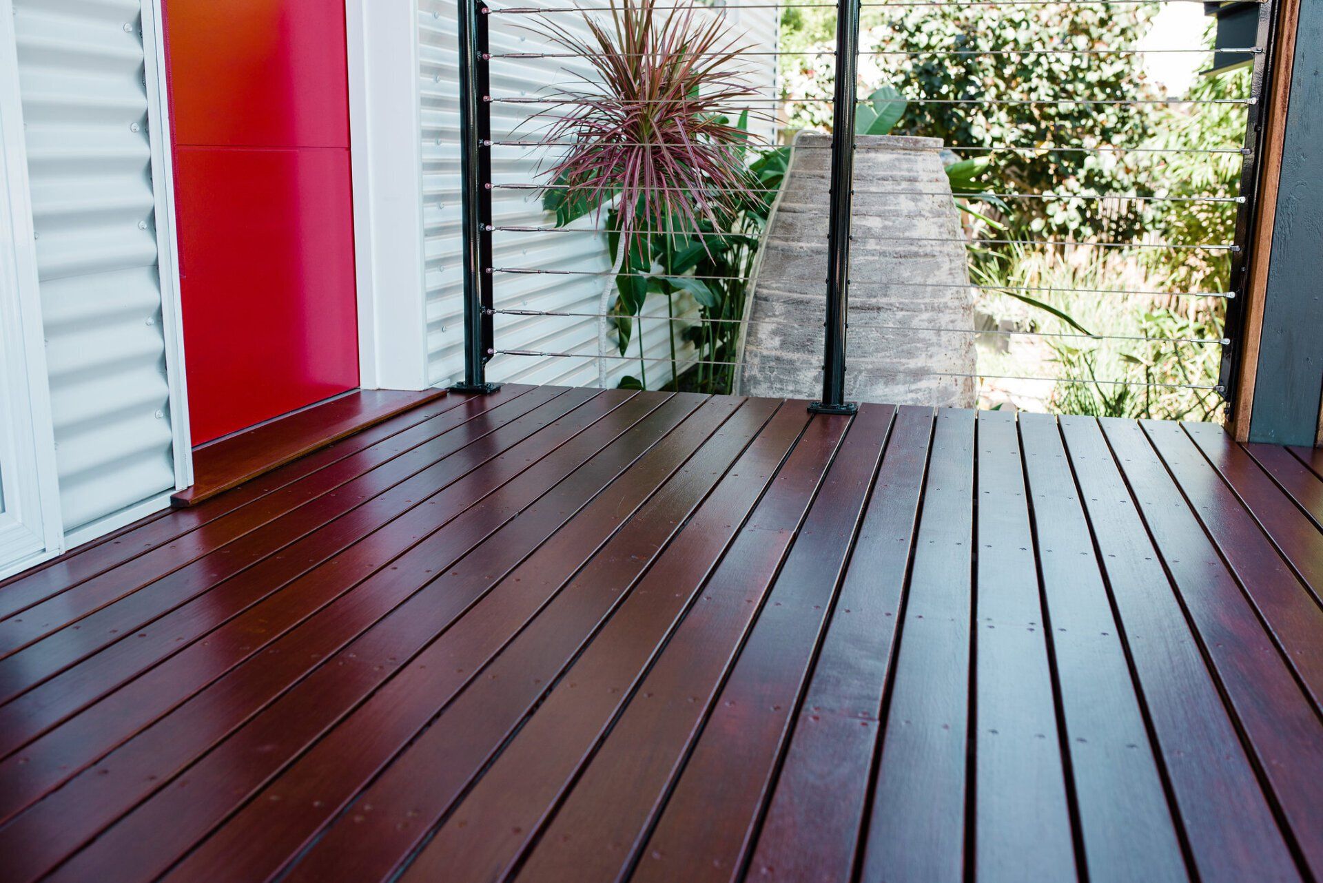 A Wooden Deck With Red Door in the Background — Attention to Detail Cleaning Services & Deck Coating Darwin in Casuarina, NT