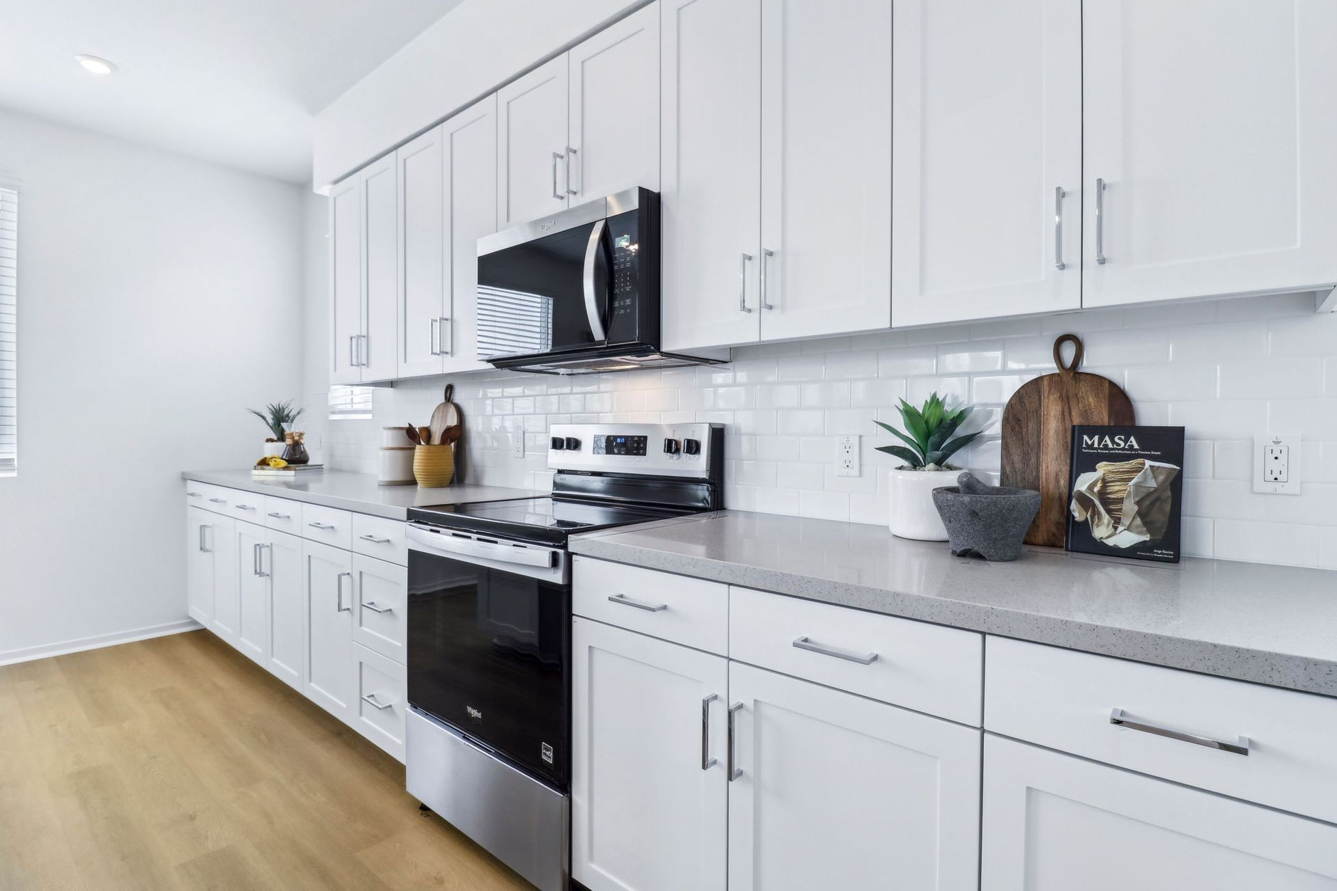 White kitchen with stainless steel appliances and light countertops.