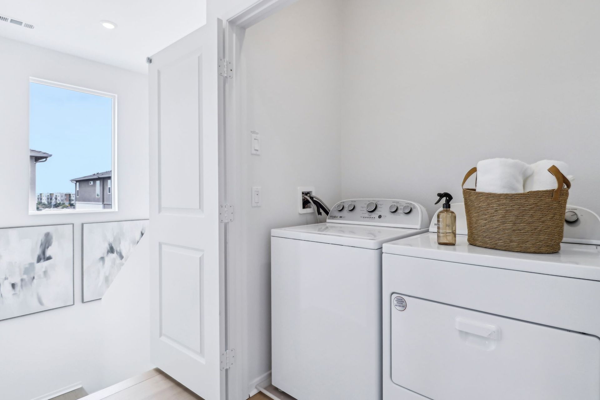 Laundry room with white appliances, a wicker basket, and a window.