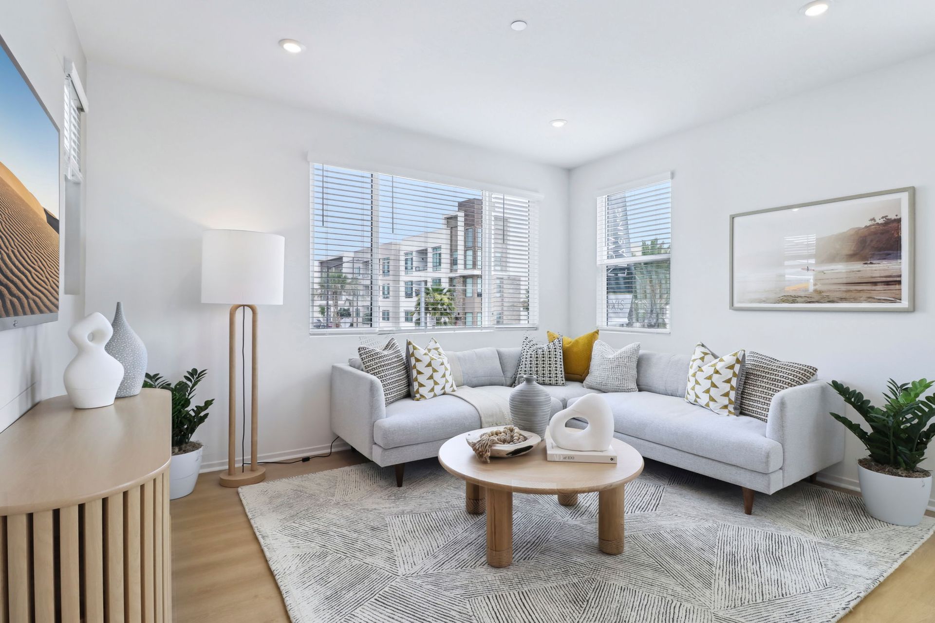 Modern living room with white sectional sofa, round coffee table, and large window.