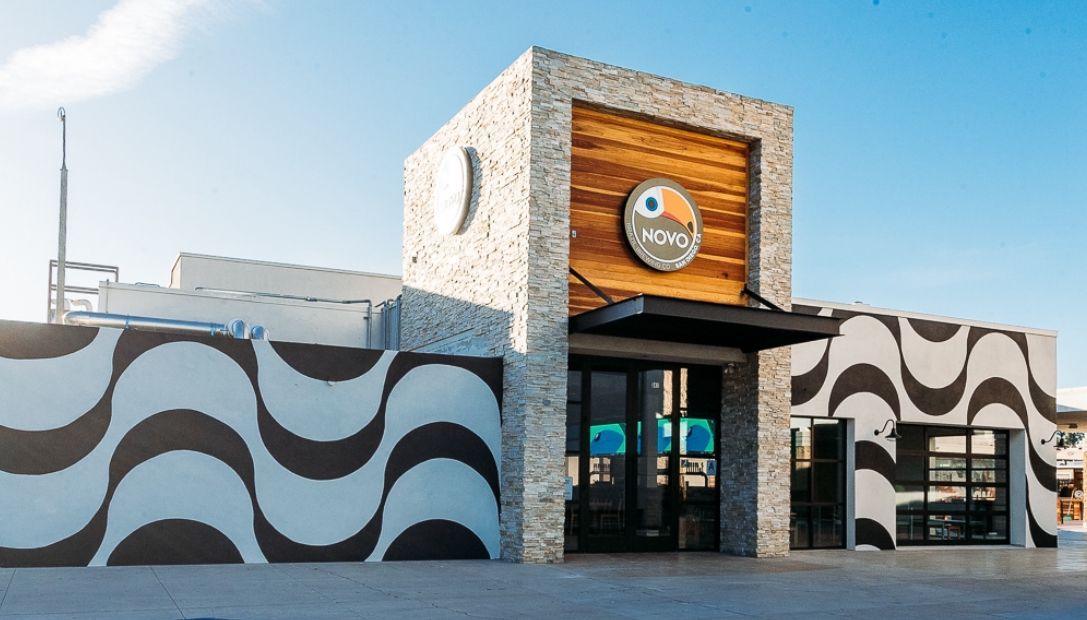 Modern building with black and white wave pattern walls, wooden door, and logo.