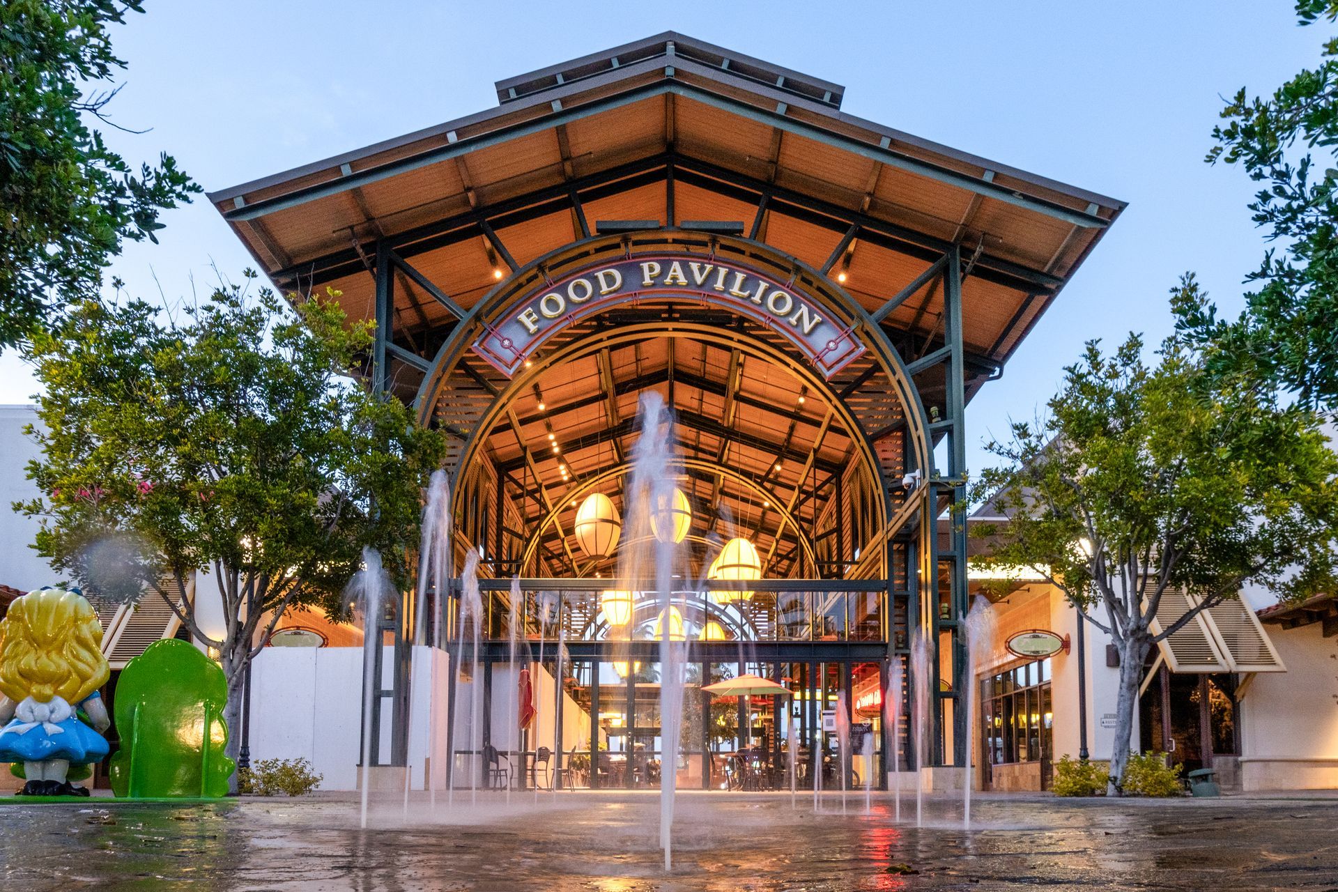 Food Pavilion with fountain, arched entrance, and trees.