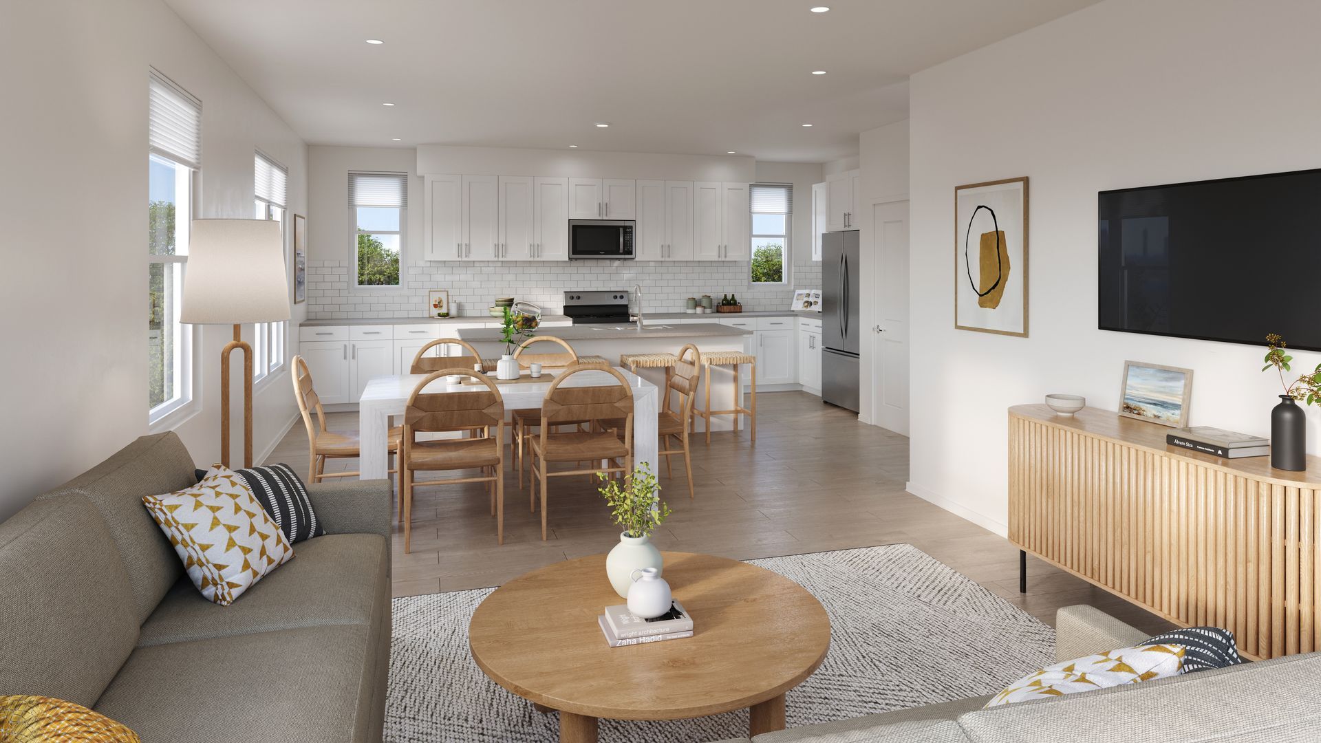 Open-concept living space: white kitchen, dining table, sofa, TV, and wooden accent console.