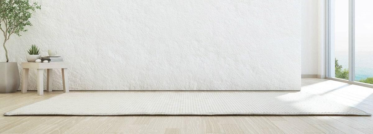 Una sala de estar vacía con una pared blanca y una alfombra en el suelo.