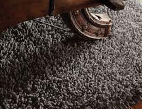 Un primer plano de una alfombra gris sobre un suelo de madera.
