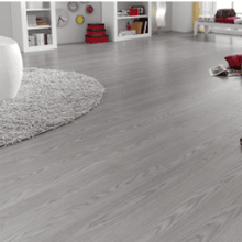 Una sala de estar con pisos de madera, un sofá, sillas y una mesa.