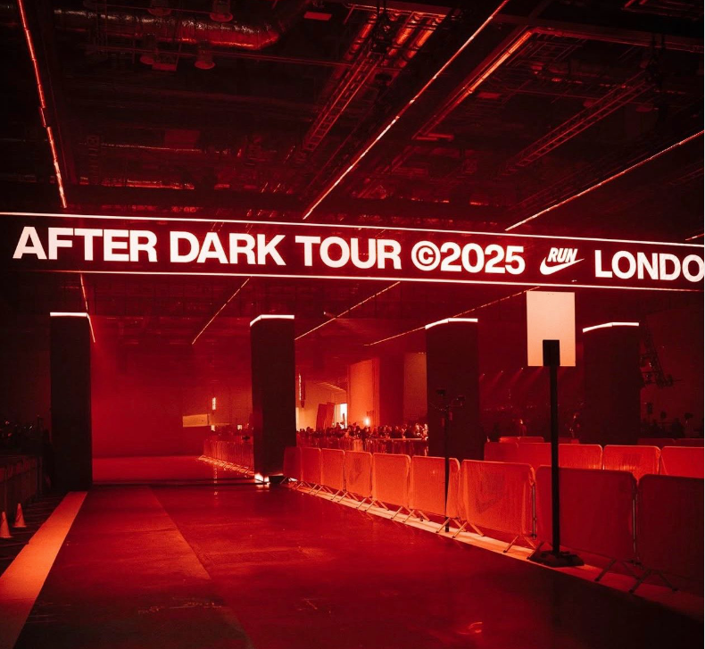 Red-lit race start line with barricades and sign reading “AFTER DARK TOUR 2025” and “LONDON”