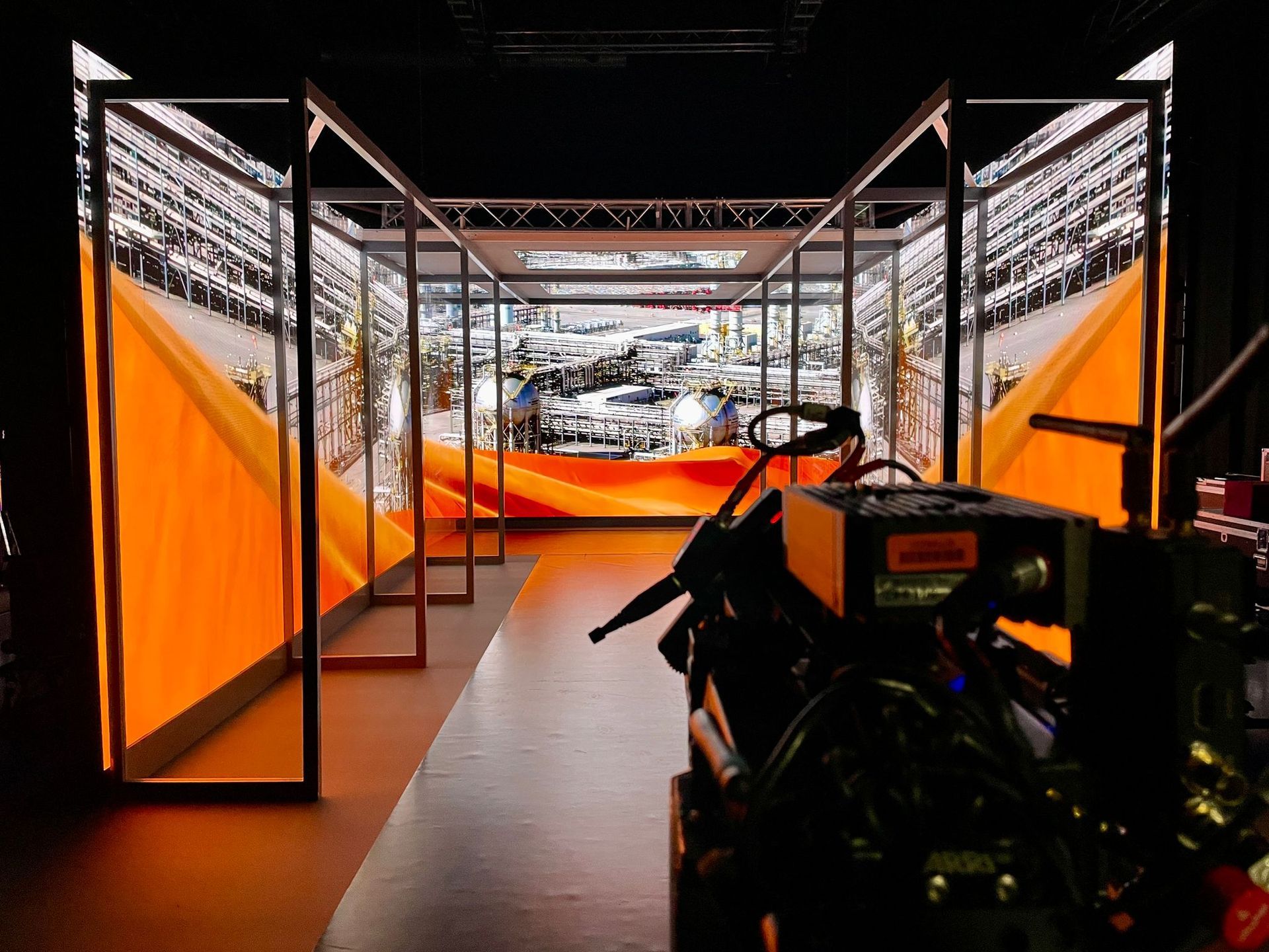 Bright orange and black exhibit tunnel with large screens and a vehicle at the end