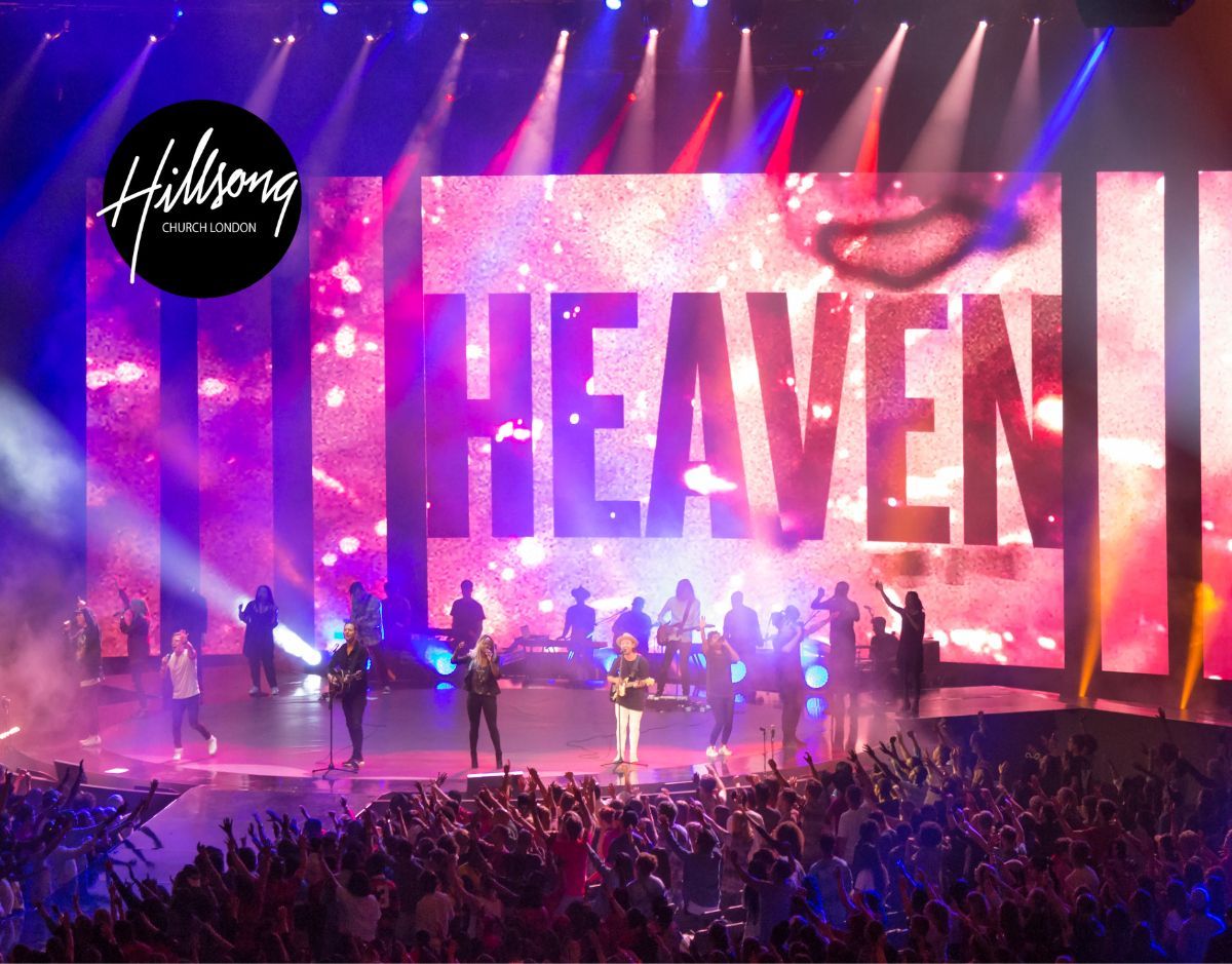 Concert stage with giant “HEAVEN” screen, purple lights, performers, and cheering crowd.