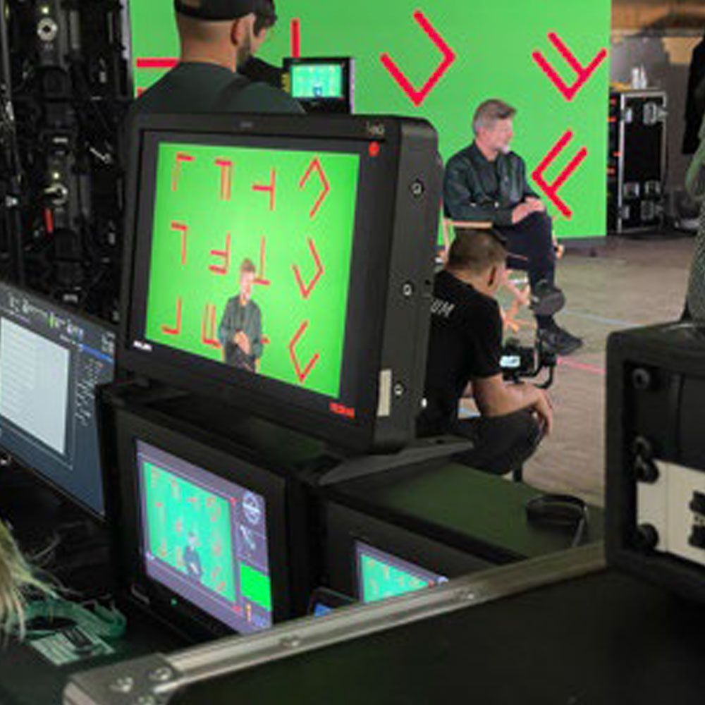 A group of people are sitting in front of a green screen