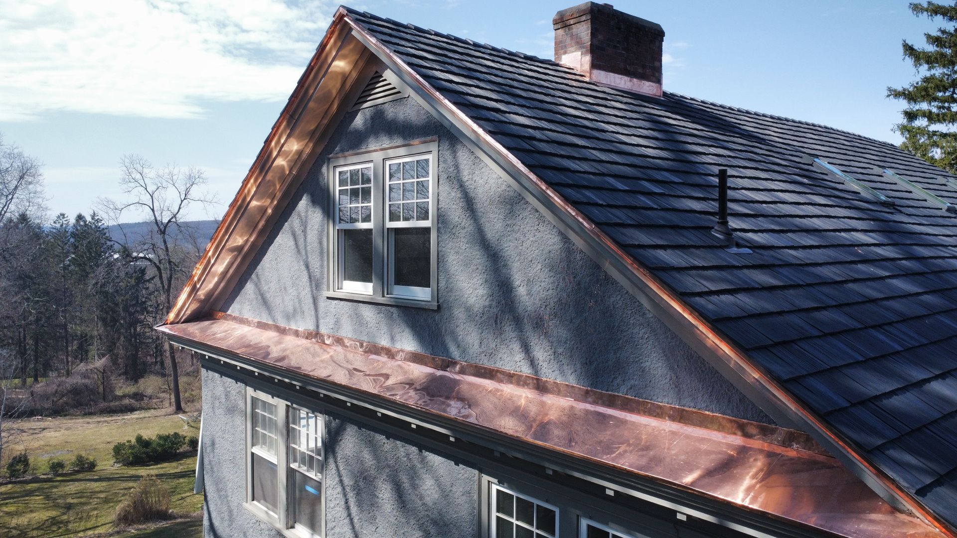 A house with a copper roof and a chimney Brava synthetic shake roof with copper trim installed in Amherst MA