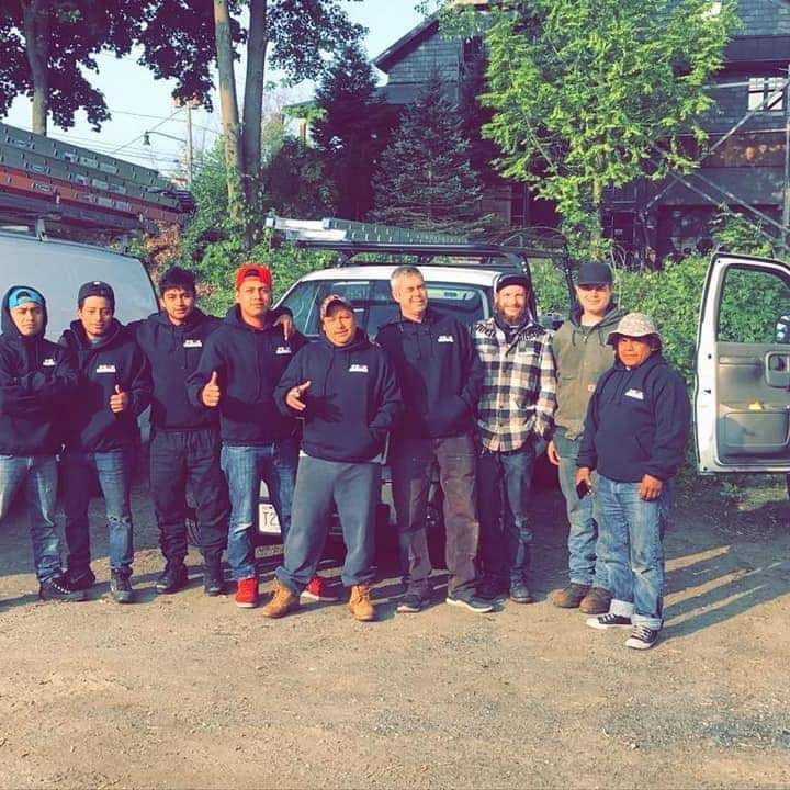 A group of men is posing for a picture in front of a truck. Peak Performance Roofing owner James Flannery with roofing crew