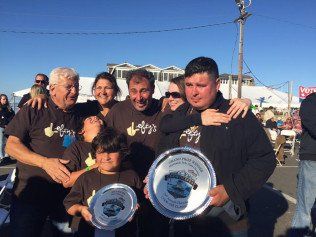 A group of people are posing for a picture while holding trophies.