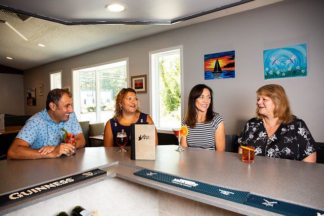 A group of people are sitting at a bar drinking drinks.