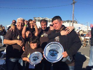 A group of people are posing for a picture while holding trophies.