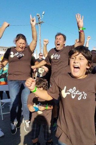 A group of people wearing lefty 's shirts are jumping in the air.