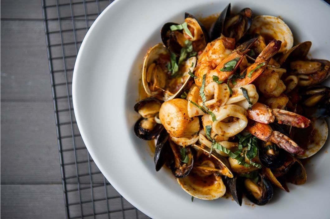 A white plate topped with seafood and sauce on a table.