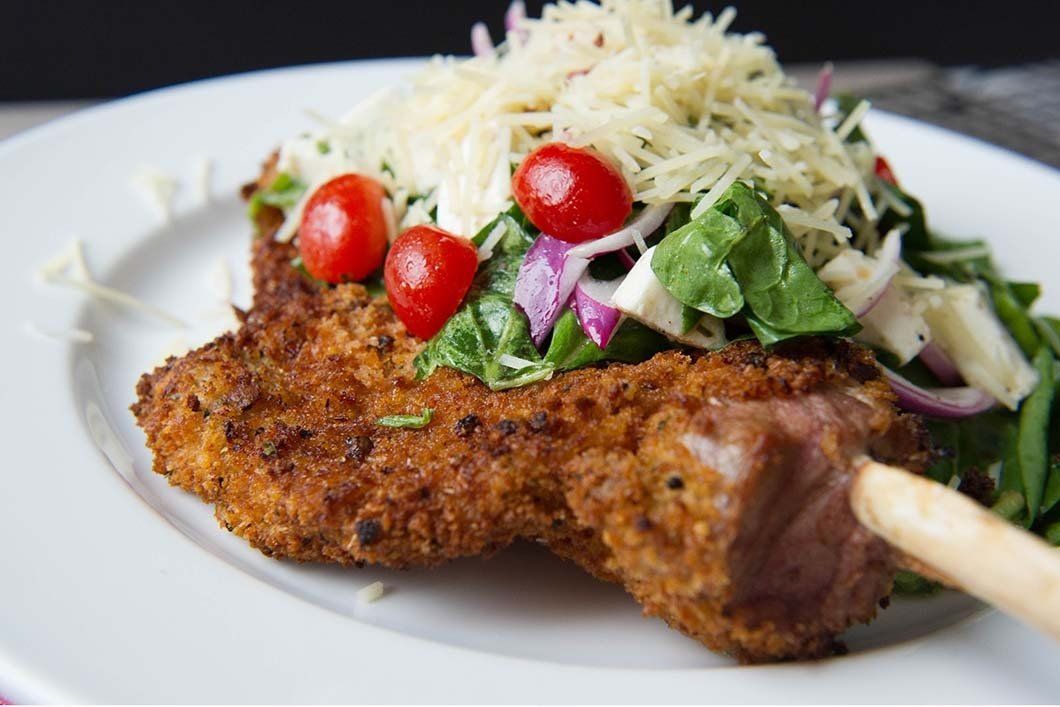 A white plate topped with a piece of meat and a salad.