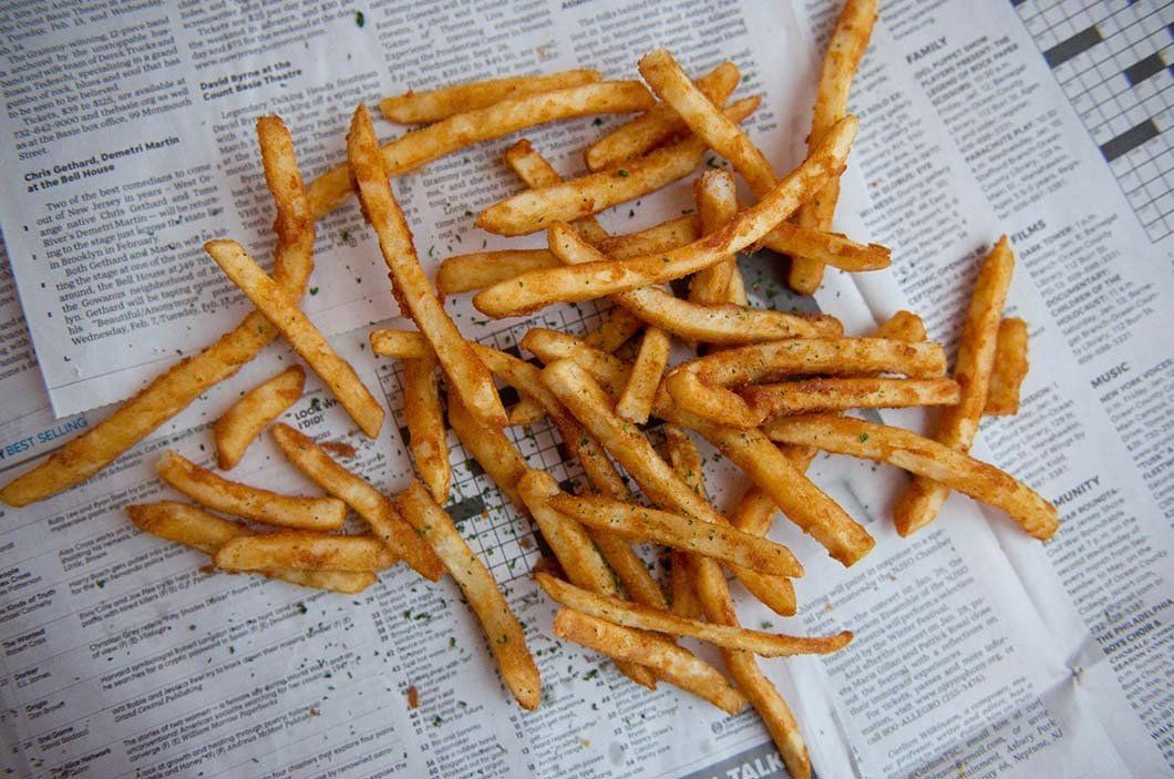 A pile of french fries sitting on top of a newspaper.