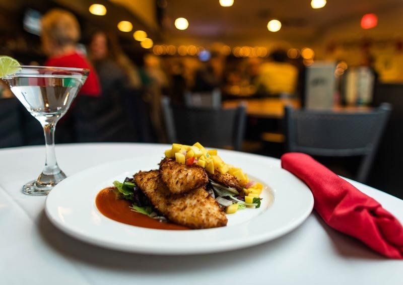 A plate of food is on a table next to a martini glass.