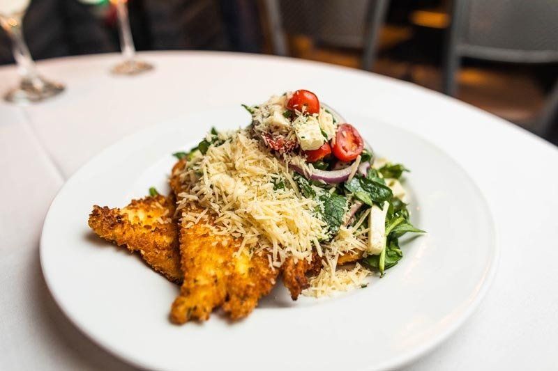 A white plate topped with fried chicken and a salad on a table.