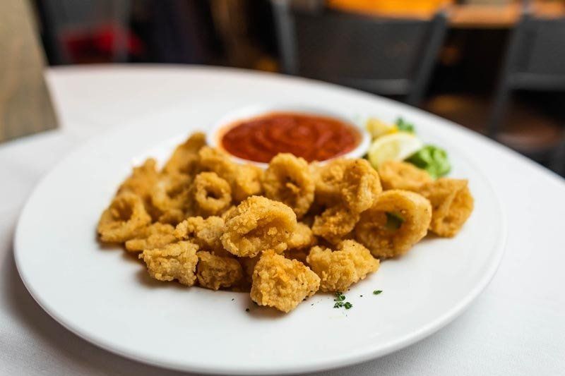 A white plate topped with fried calamari and sauce on a table.