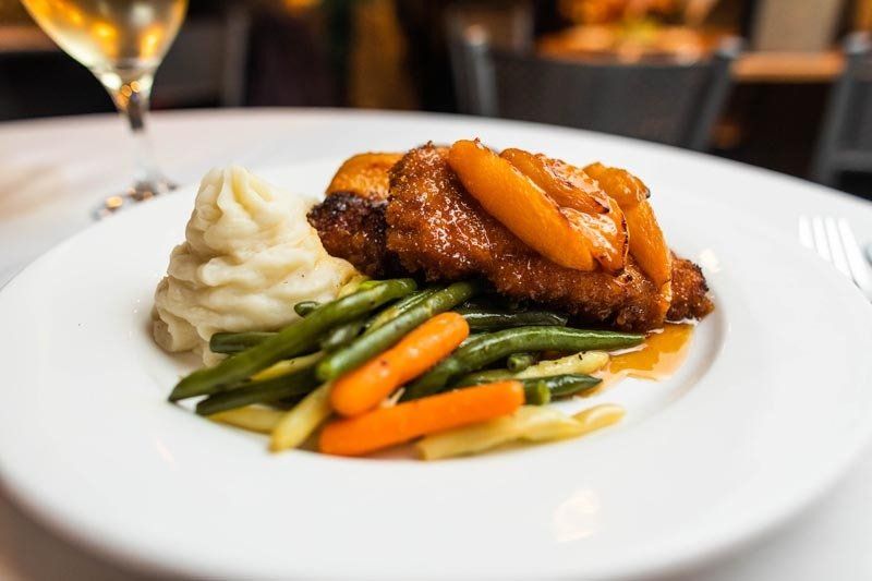 A white plate topped with meat , mashed potatoes , green beans and carrots.