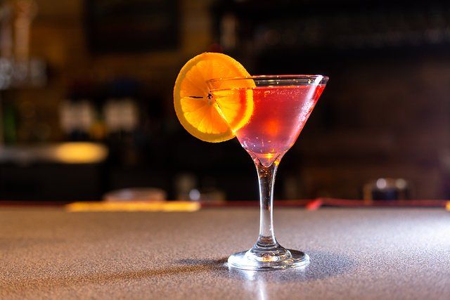 A martini with an orange slice on a bar counter.