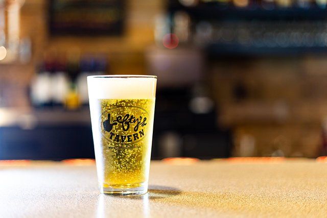 A glass of beer is sitting on a counter.