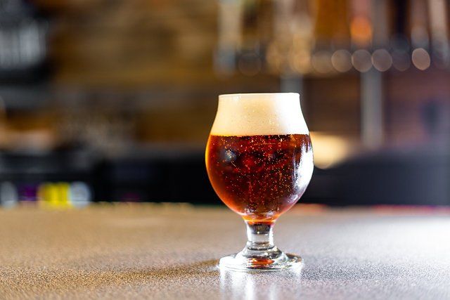 A glass of beer is sitting on a bar counter.