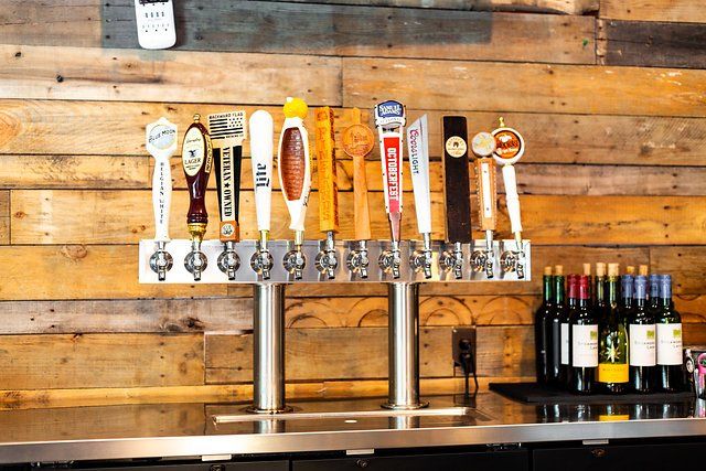 A bar with a lot of beer taps and bottles of wine.