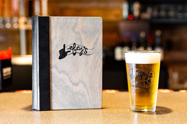 A menu and a glass of beer are on a table.