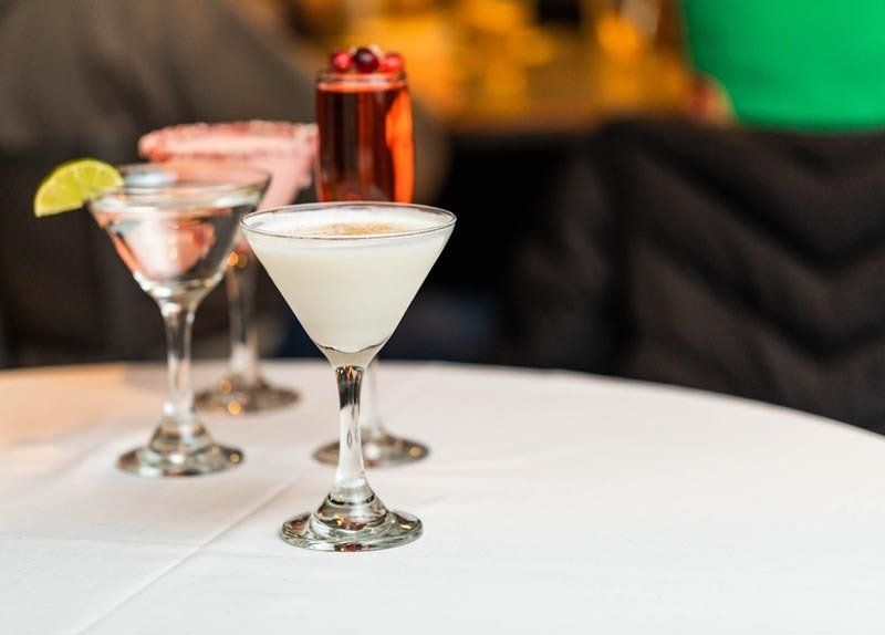 Three martini glasses are sitting on a white table.