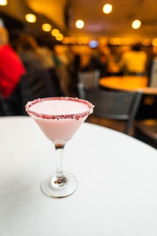 A pink cocktail in a martini glass on a table