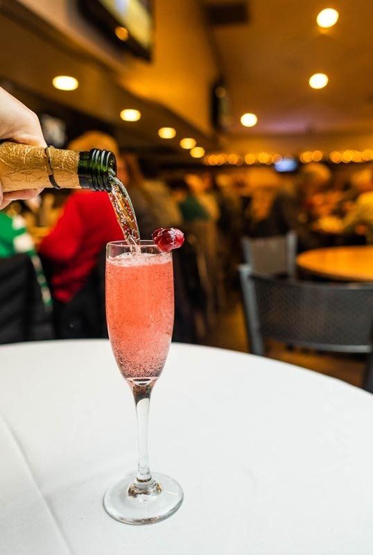 A person is pouring a drink into a glass on a table.