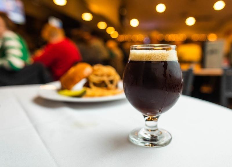A glass of beer is sitting on a table next to a plate of food.