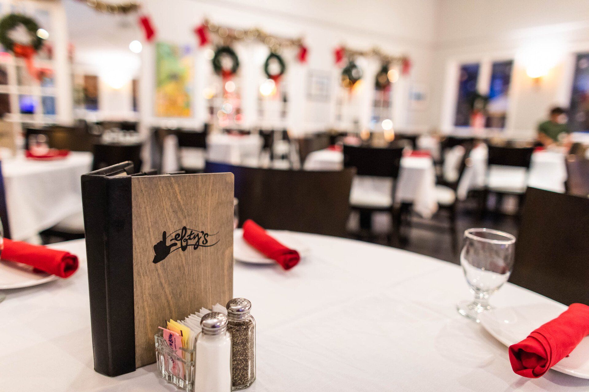 A restaurant with a menu , salt and pepper shakers , and a wine glass on a table.